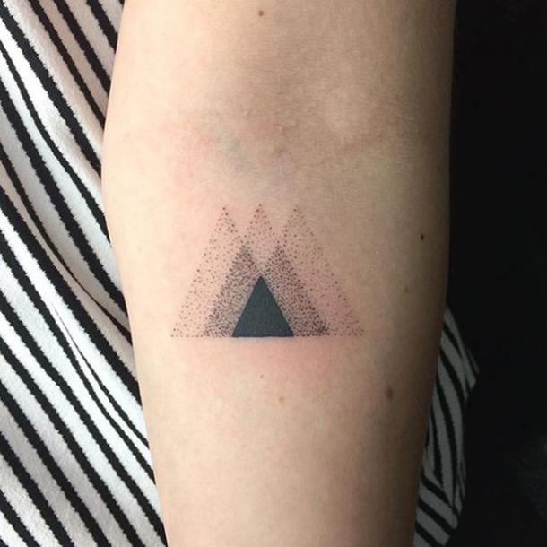 Applying a tattoo of a triangle.