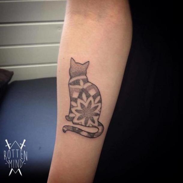 A tattoo of a cat looking away.