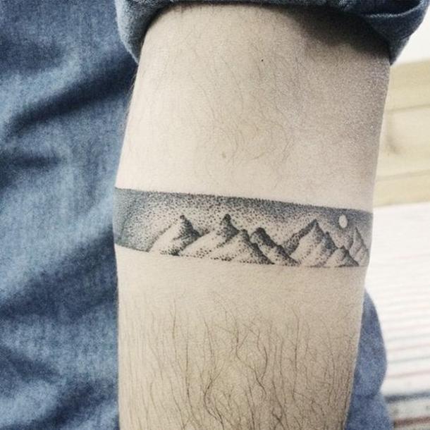 Thin ribbon tattoo of mountains in dotwork style