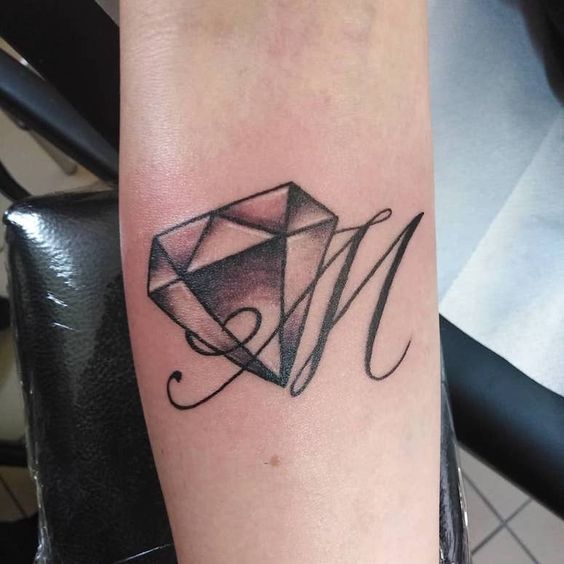 Tattoo of a diamond on the hand with a letter