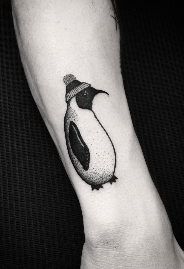 Tattoo of a penguin on the arm in black and gray style