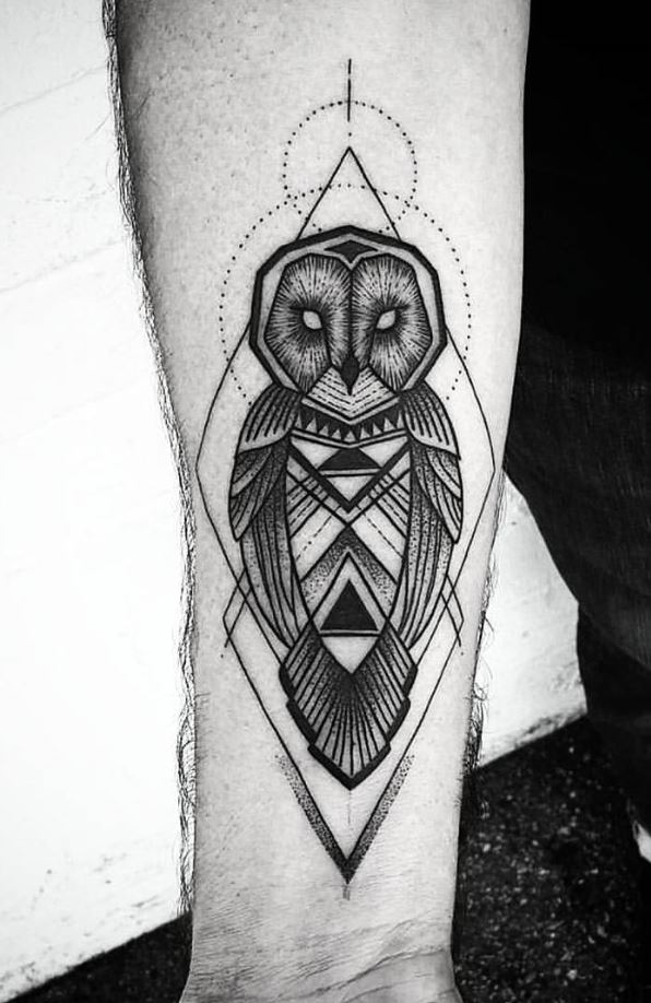 Tattoo of an owl on the arm in black and gray style