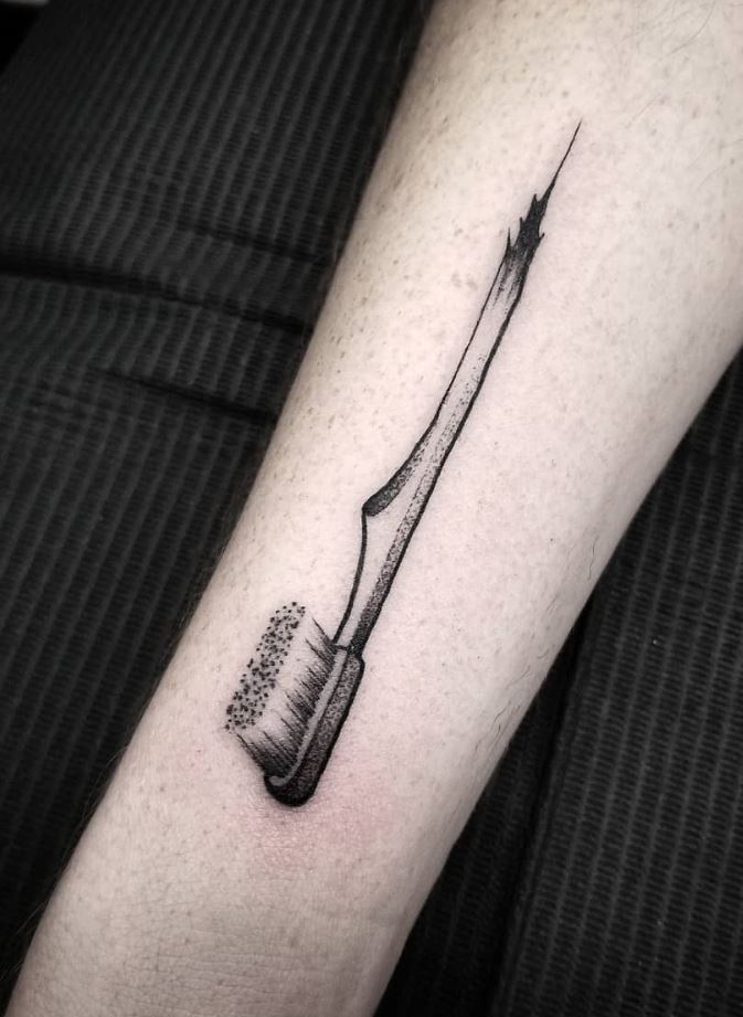 black and gray toothbrush tattoo on my arm