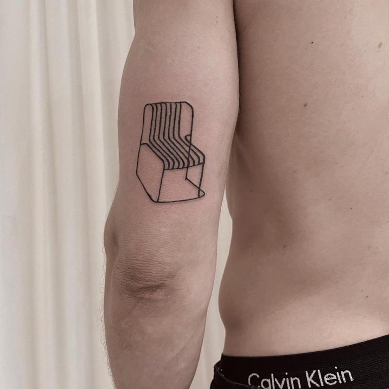 Armchair tattoo on bicep in minimalist style