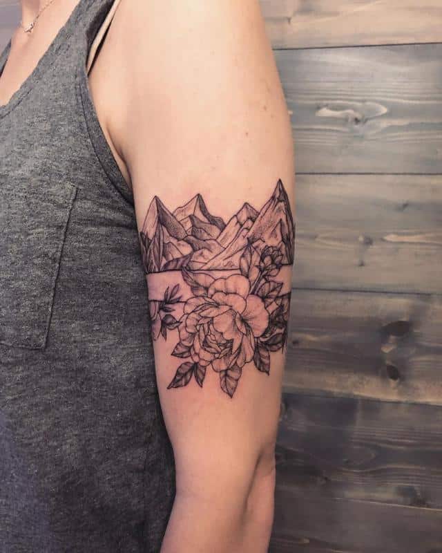 Tattoo of mountains and flowers on the biceps