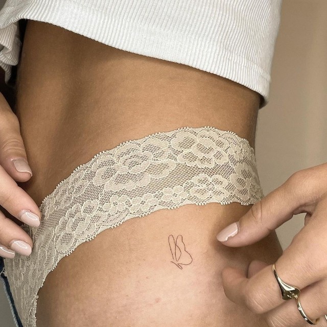 Minimalist butterfly line tattoo on the thigh