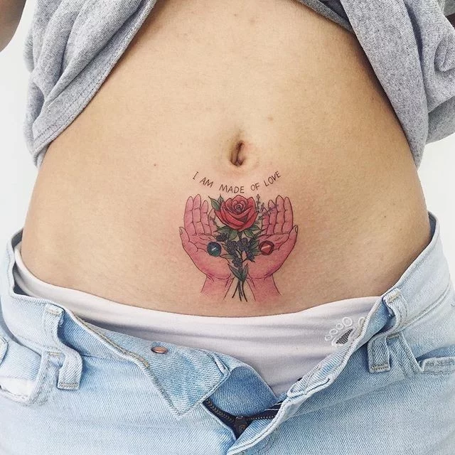 Tattoo of a flower in hand on the abdomen