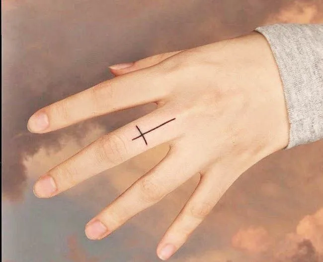 Tattoo of a cross on the middle finger