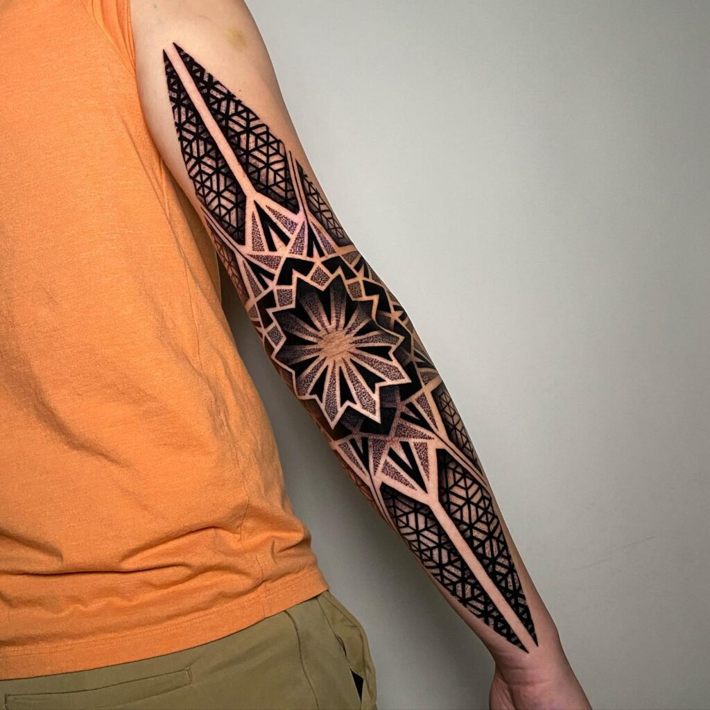 Black tattoo on the elbow with a mandala on the arm