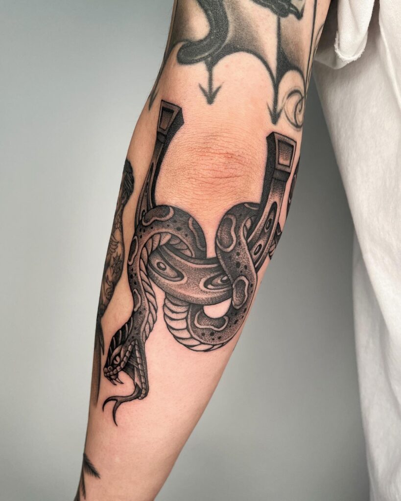 Black tattoo with a snake on the elbow