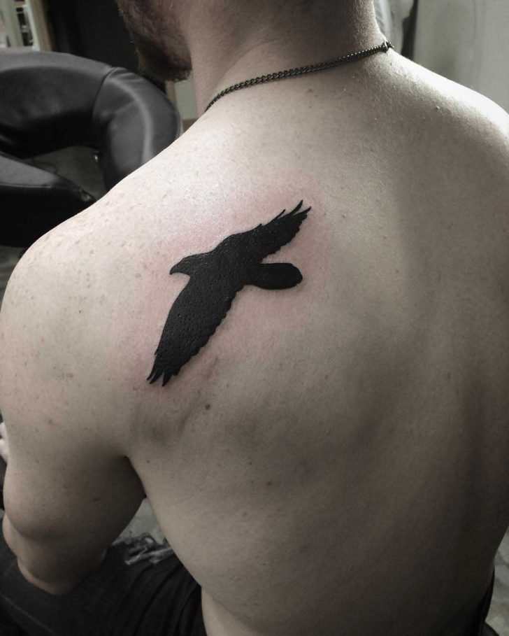 Tattoo of a black bird on the shoulder blade