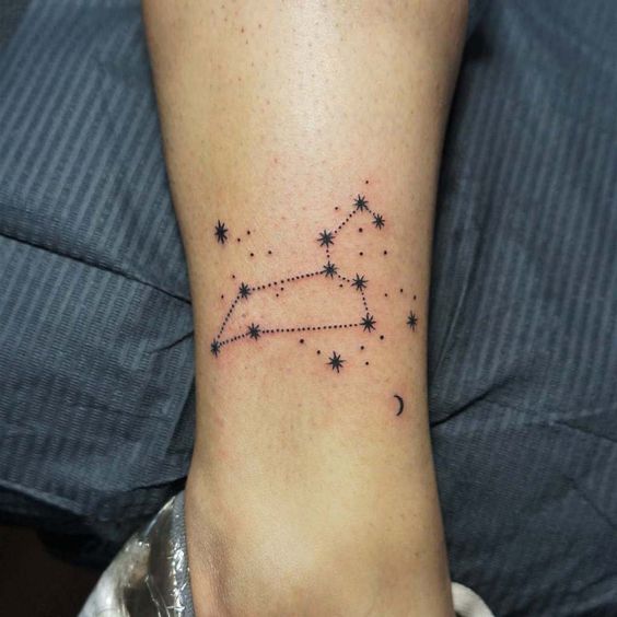 Tattoo of the constellation zodiac sign lion on the shin for women