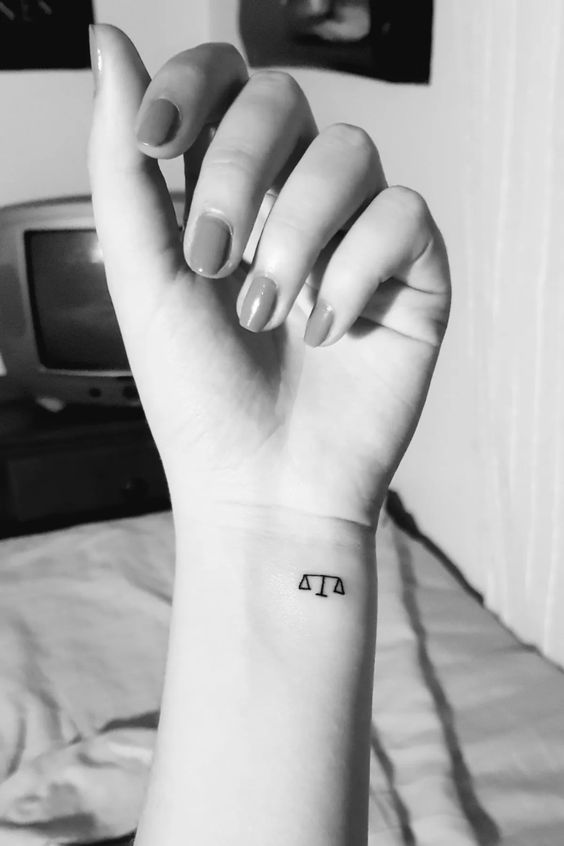 Tattoo of the zodiac sign Libra on the wrist for women