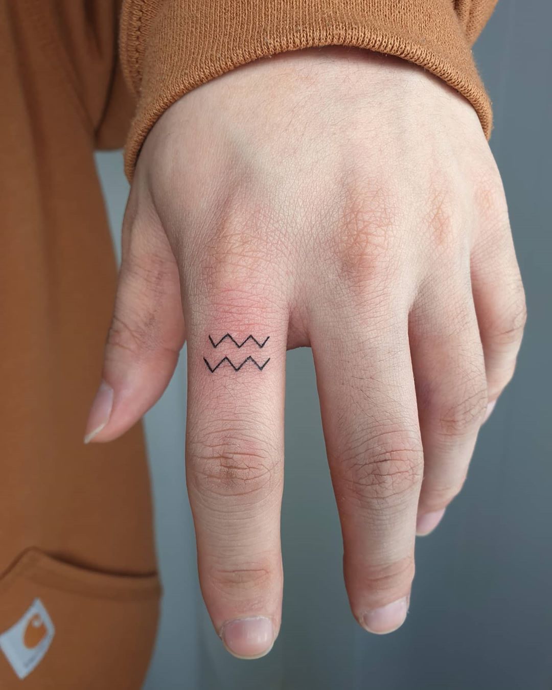 Tattoo of the zodiac sign Aquarius on the finger for men