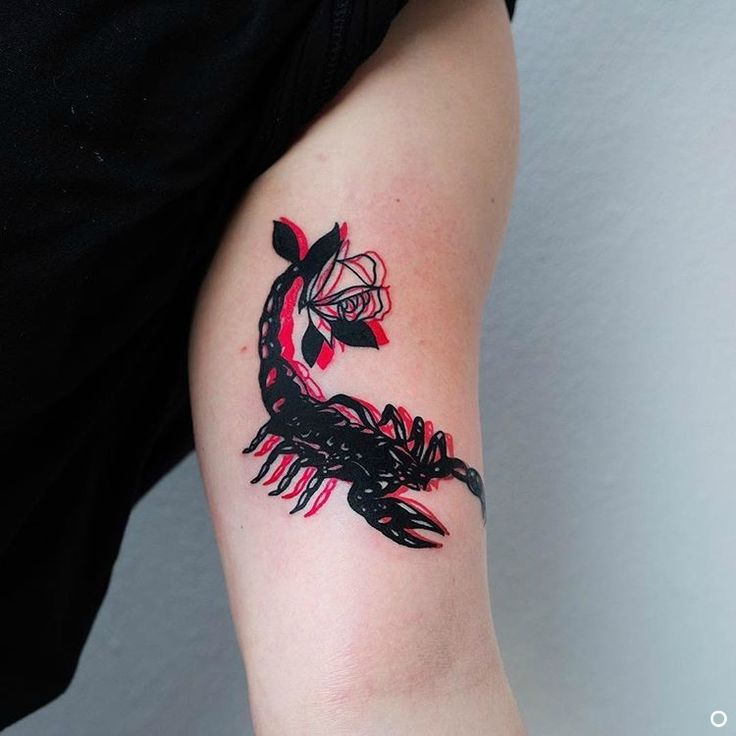 Tattoo of the zodiac sign of a scorpion on the biceps for women