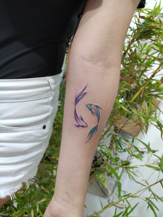 Tattoo of the fish zodiac sign on the forearm for women