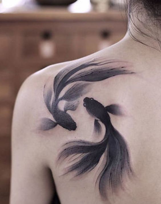 Tattoo of the zodiac sign of a fish on the shoulder blade for men