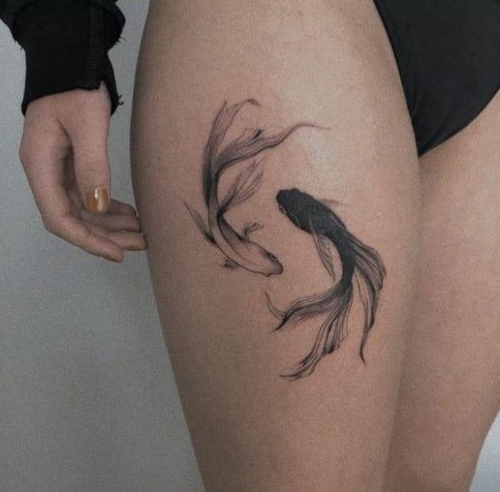 Tattoo of the fish zodiac sign on the thigh for women