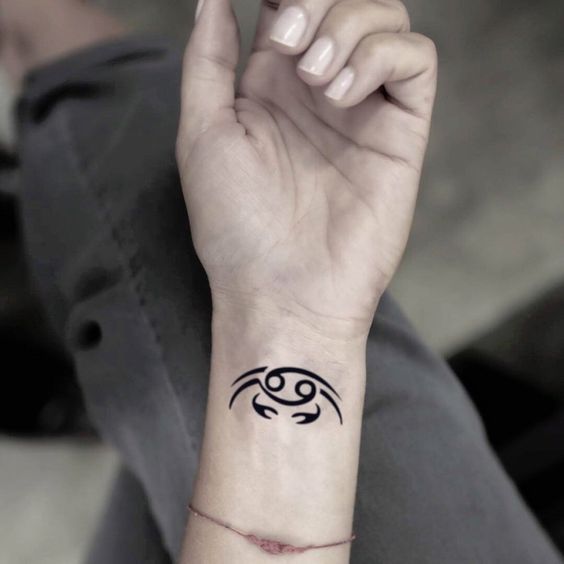 Tattoo of the zodiac sign of Cancer on the wrist for women