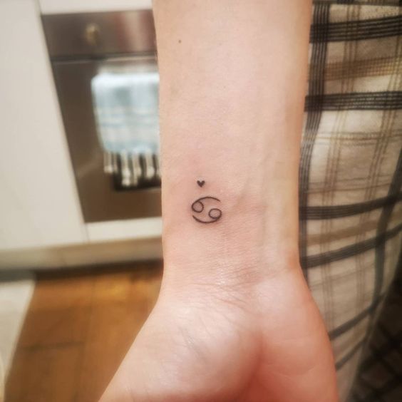 Tattoo of the zodiac sign of Cancer on the wrist for women