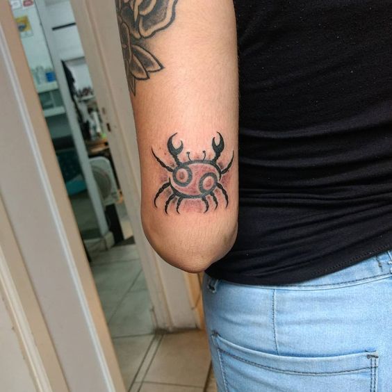 Tattoo of the zodiac sign crab on the elbow for women