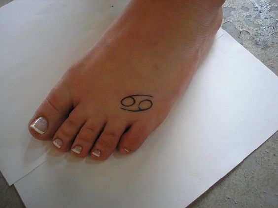 Tattoo of the zodiac sign of Cancer on the foot for women