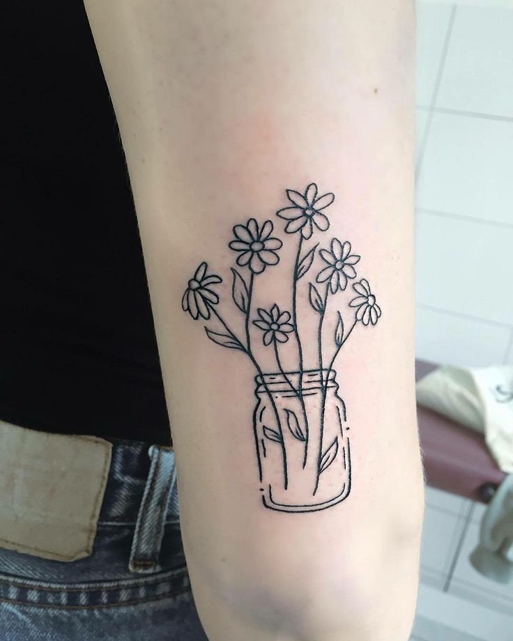 Tattoo of a daisy in a jar on the forearm for women