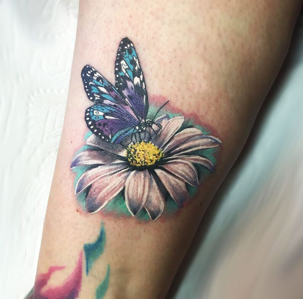 Colorful daisy tattoo with a butterfly on the shin for women