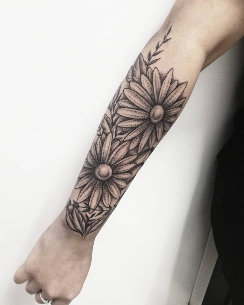 Large daisy tattoo on the forearm for women