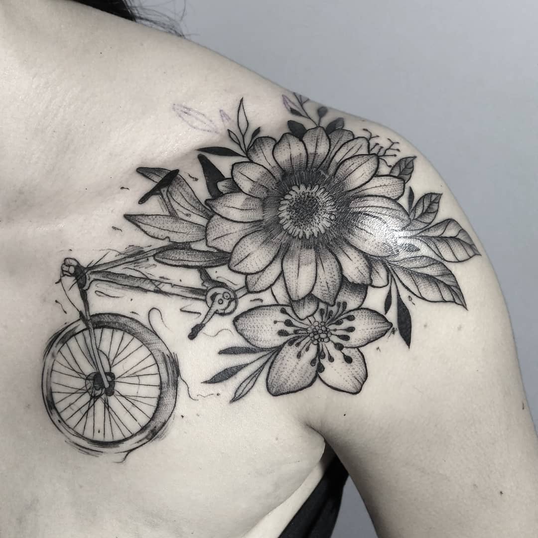 Daisy tattoo with a bicycle on the shoulder for women