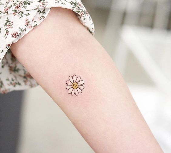 Small daisy tattoo on the forearm for women