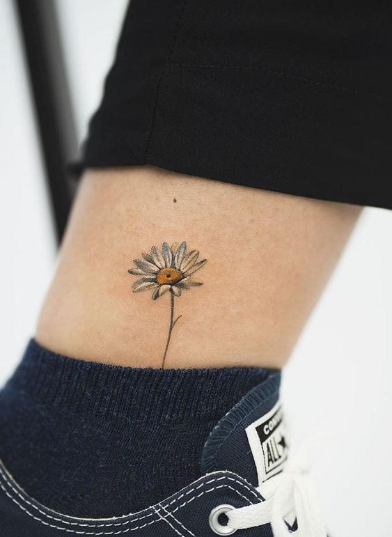 Colorful daisy tattoo on the shin for women