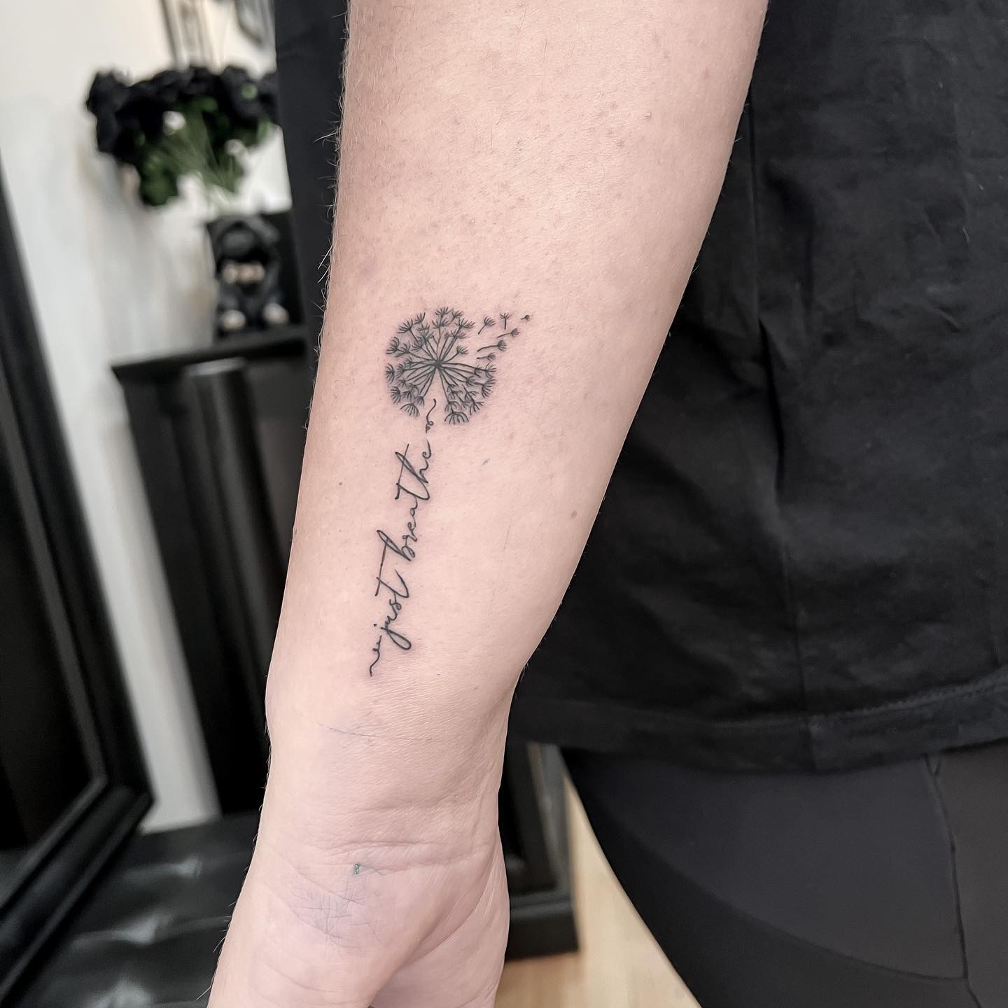 Small tattoo of a dandelion with an inscription on the forearm for men