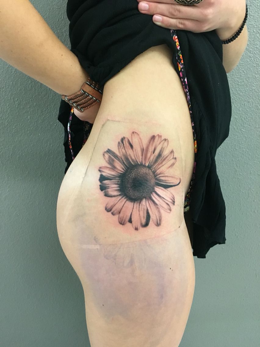 Large daisy tattoo on the thigh for women