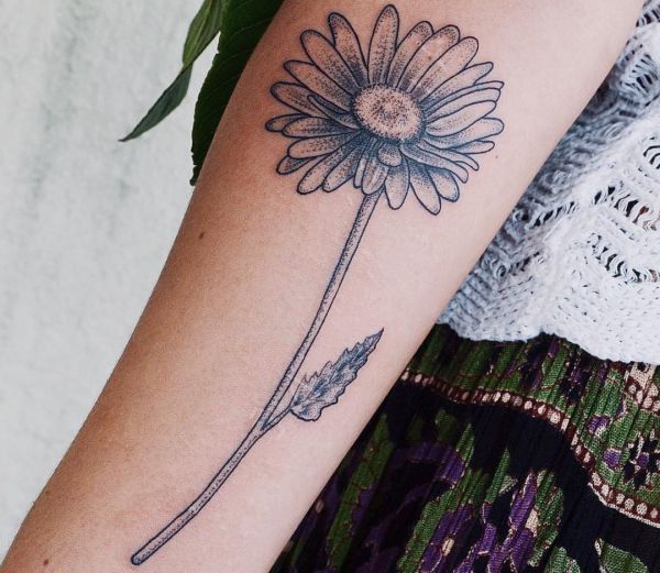 Large daisy tattoo on the forearm for women