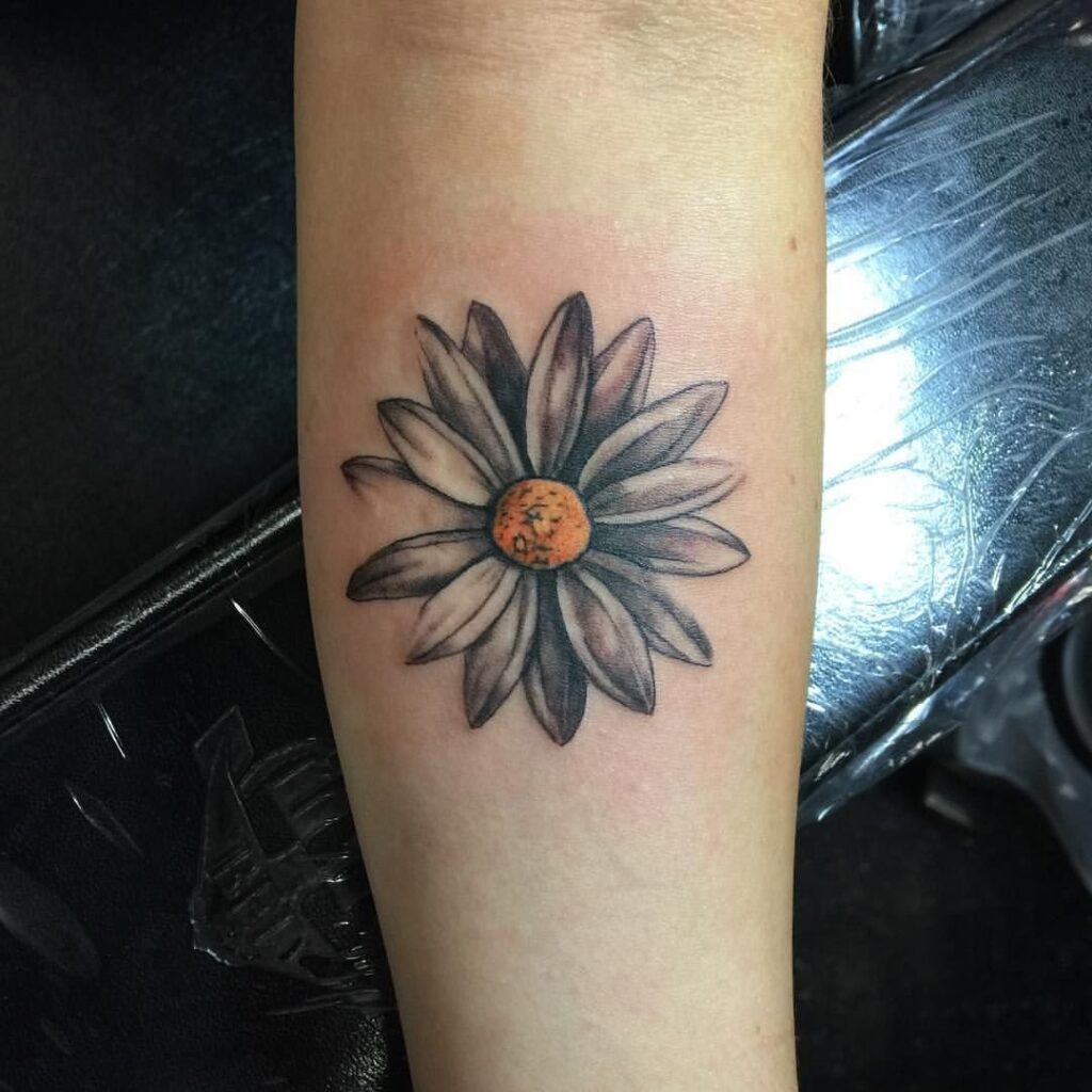 Large daisy tattoo on the forearm for women