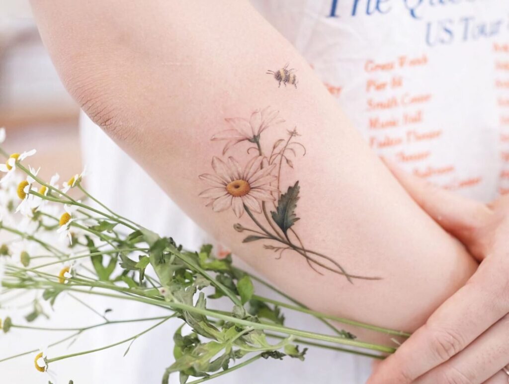 Colorful daisy tattoo on the forearm for women