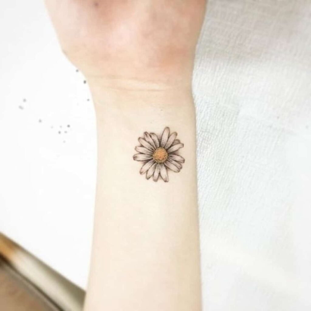 Small daisy tattoo on the wrist for women