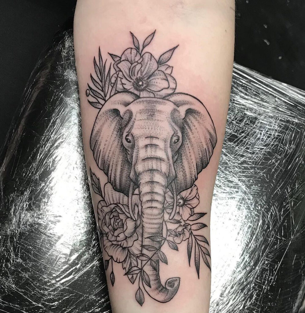 Elephant tattoo with flowers on the forearm for women