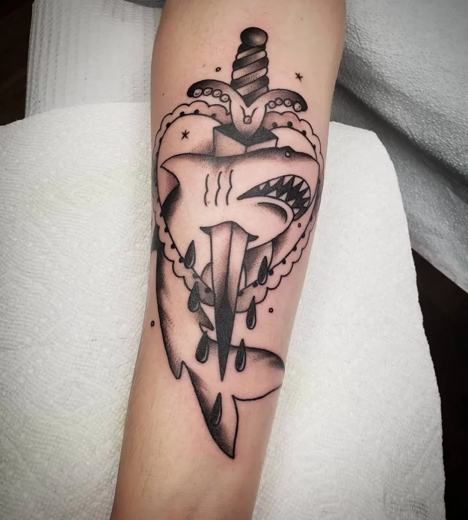 Shark tattoo with a knife on the forearm for women