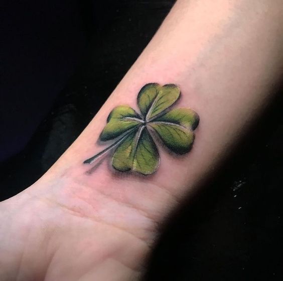 Colored clover tattoo on the forearm for women