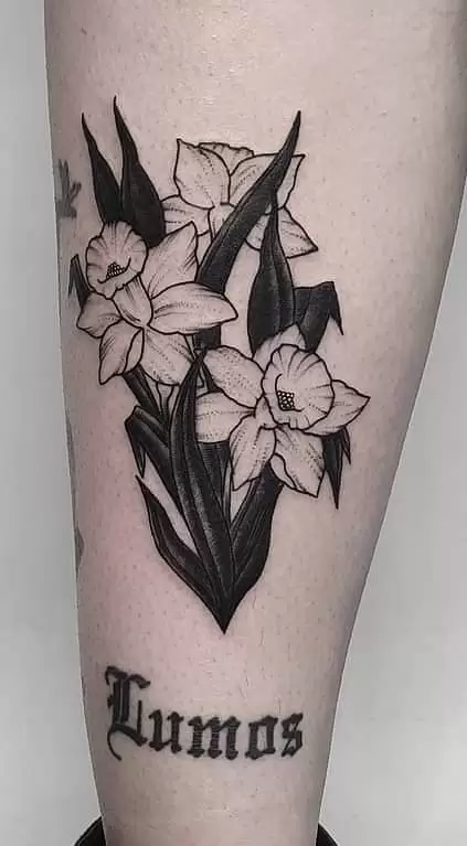 Tattoo of a daffodil flower with an inscription on the foot for men