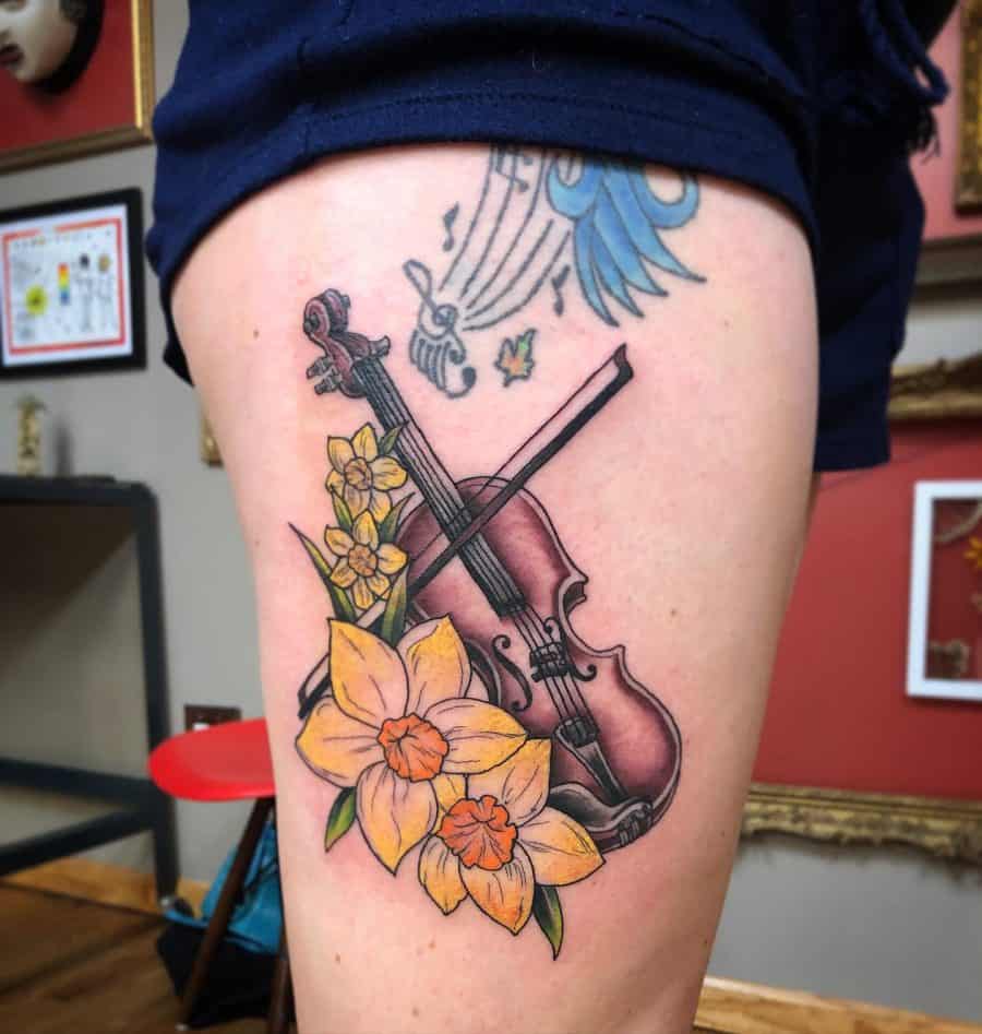 Daffodil flower tattoo with violin on the thigh for women