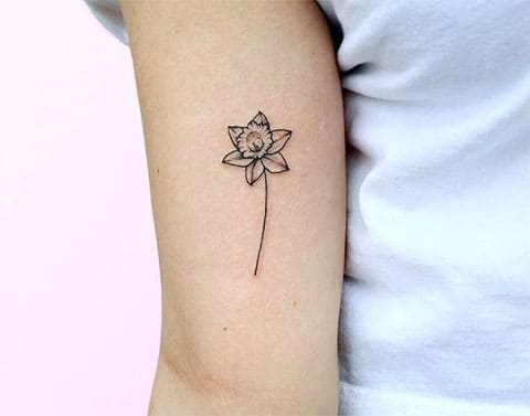 Small tattoo of a daffodil flower on the shoulder for women