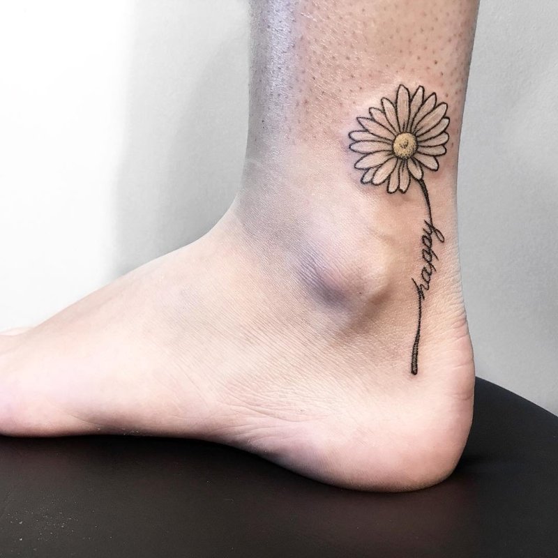 Colorful ankle tattoo of a daisy with an inscription for women