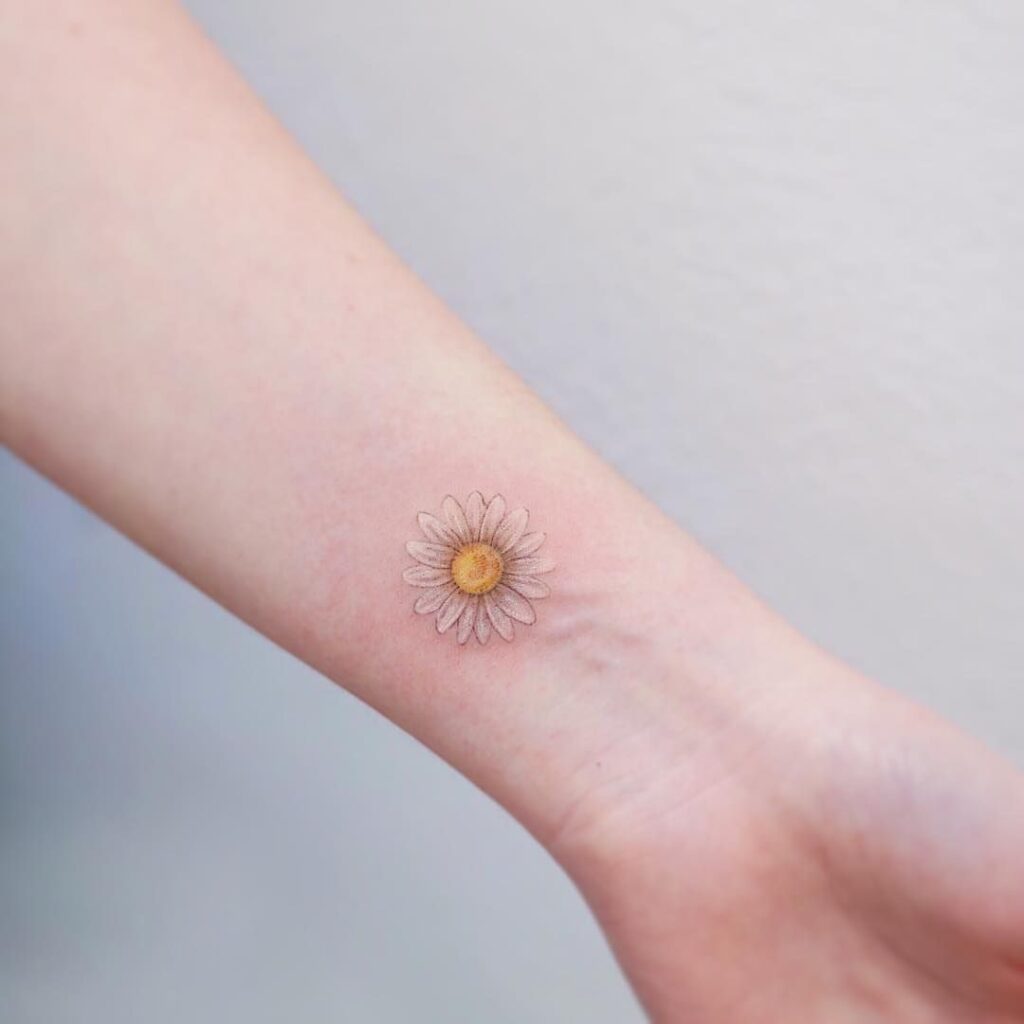 Small daisy tattoo on the wrist for women