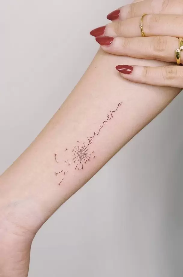 Dandelion tattoo with an inscription on forearm for women