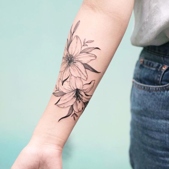 Tattoo of two lilies on the forearm for women