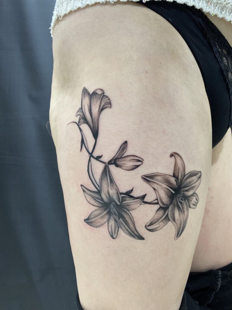 Large lily tattoo on the thigh for women