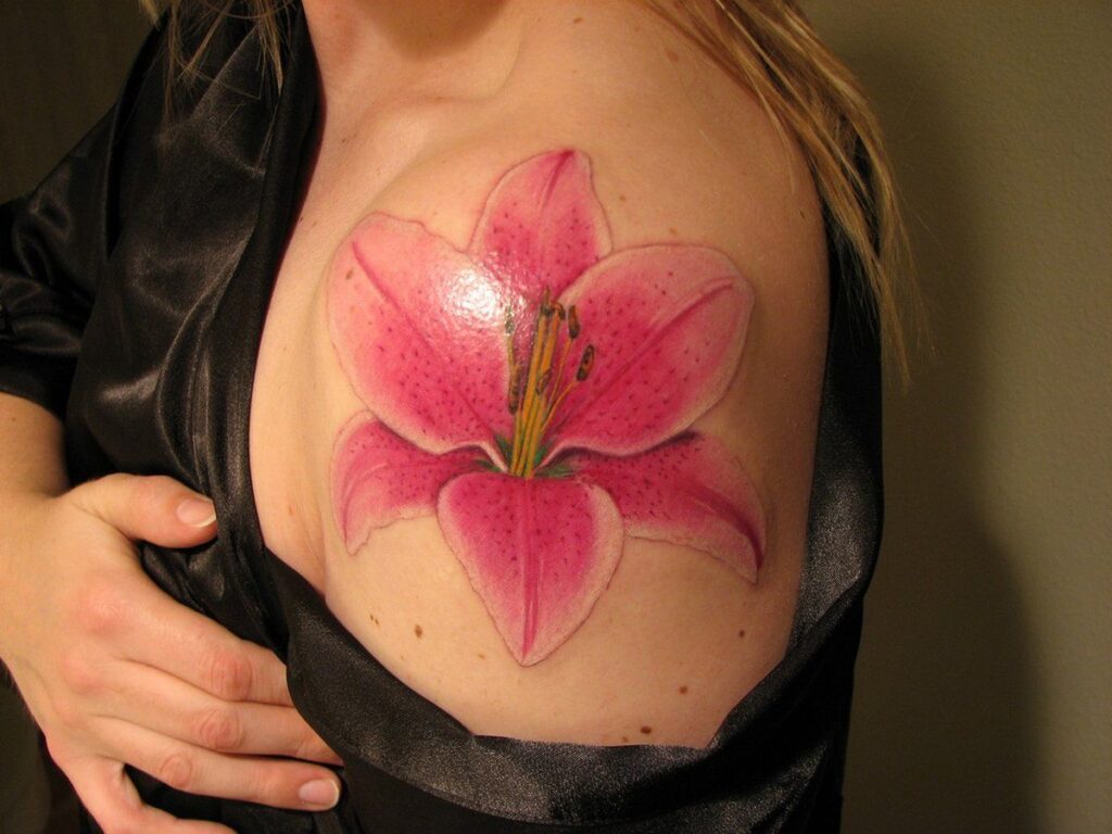 Colorful tattoo of a large lily on the shoulder for women